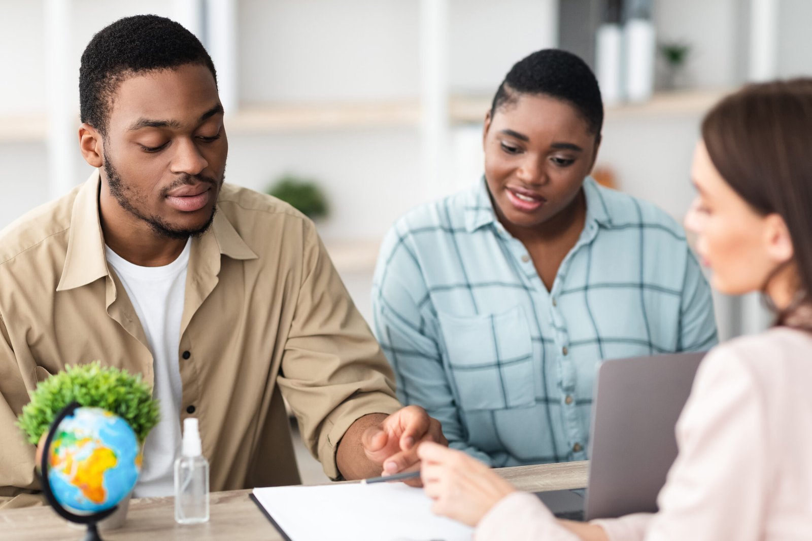 African Tourists Couple Signing Papers During Consultation In Travel Agency